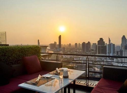 a table on a balcony with a view of a city at Sathorn Prime Residence & Rooftop Sky Bar in Bangkok