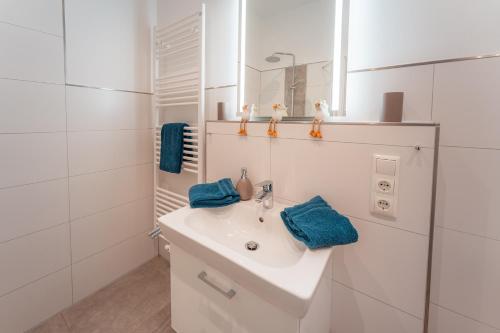 a white bathroom with a sink and a mirror at Apartment Strandzauber, Am Alten Deich 4-6 Whg 11 in Dangast