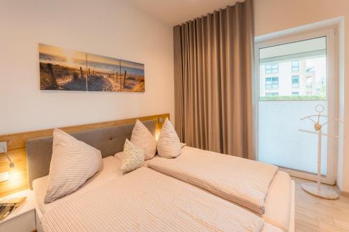 a bedroom with a bed with pillows and a window at Apartment Strandzauber, Am Alten Deich 4-6 Whg 11 in Dangast