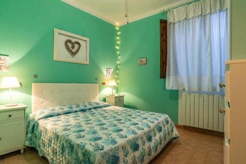 Un dormitorio con una cama y una pared verde. en Green View Apartment with pool, en Castiglioncello