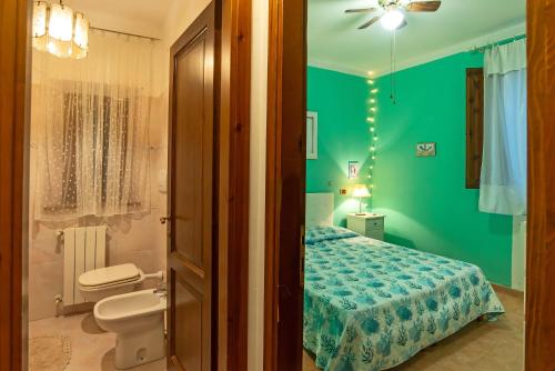 1 dormitorio verde con 1 cama y baño en Green View Apartment with pool, en Castiglioncello