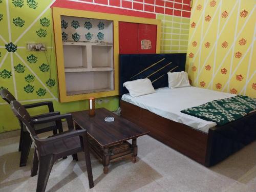 a bedroom with a bed and a table and a chair at Krishna Home Stay in Mathura