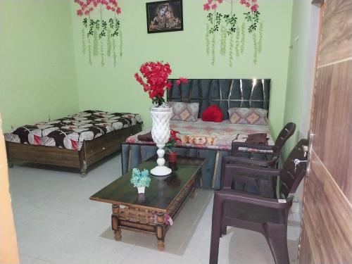 a living room with a couch and a table with flowers at Krishna Home Stay in Mathura