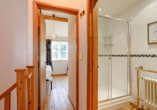 a bathroom with a walk in shower and a glass door at Cottage Pie in Snettisham