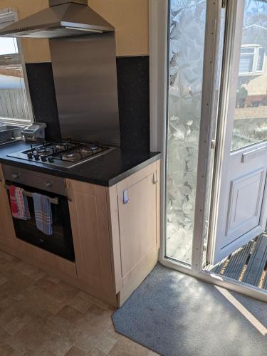 a kitchen with a stove top oven next to a window at Colins holiday home in Hull
