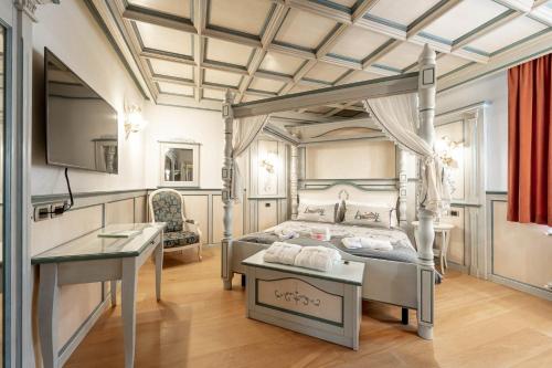 a bedroom with a canopy bed and a desk at Hotel Dolomiti Schloss in Canazei