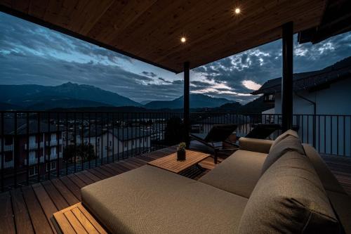 a couch on a balcony with a view of mountains at Cristallo Sport & Wellness Hotel in Levico Terme