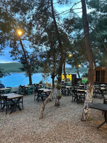 a group of tables and trees in front of a lake at Belize suit otel in Muğla