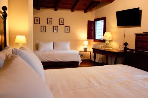 a bedroom with two beds and a desk and a television at Palazzo Minelli in Sala Bolognese