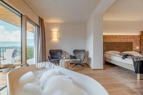レーヴィコ・テルメにあるCristallo Sport & Wellness Hotelのベッドルーム(バスタブ、ベッド1台付)、バルコニーが備わります。