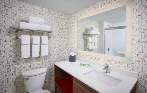 a bathroom with a toilet and a sink and a mirror at Holiday Inn & Suites Oakville at Bronte, an IHG Hotel in Oakville
