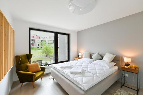 a white bedroom with a large bed and a chair at Golf Apartment 114 in Beroun