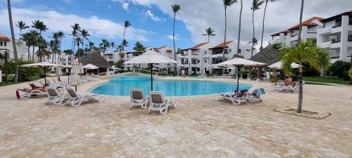 een zwembad van het resort met stoelen en parasols bij Stanza Mare I-203, On The Beach Private, Bavaro, Equipped, 2R-2B Bavaro, Punta Cana in Punta Cana