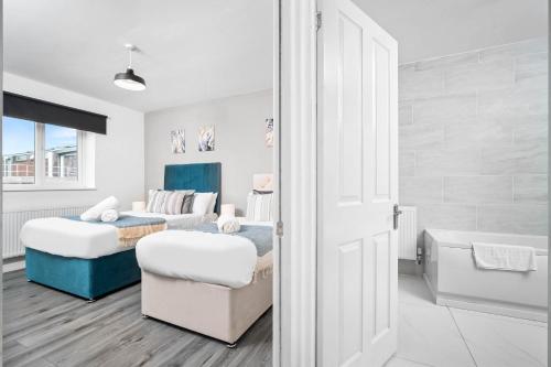 a white bedroom with two beds and a tub at Stylish Apartment - Cradley Heath - Pet Friendly - Parking - Netflix 2MH in Birmingham