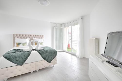 une chambre blanche avec un lit et une télévision dans l'établissement Les Sarrazines - 2 voyageurs - Parking privé, à Créteil