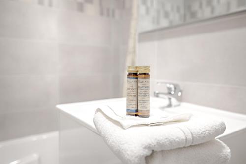 - une salle de bains blanche avec une bouteille d'alcool sur une serviette dans l'établissement Les Sarrazines - 2 voyageurs - Parking privé, à Créteil