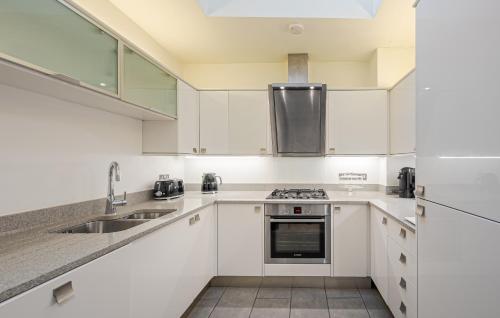 a kitchen with white cabinets and a sink and a refrigerator at Beautiful House in Knightsbridge in London