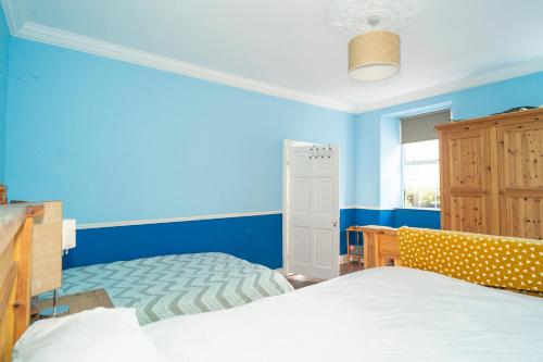 - une chambre avec des murs bleus, un lit et une fenêtre dans l'établissement Willsgrove House, à Athy