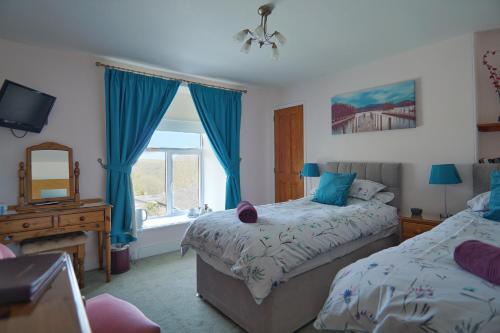 a bedroom with two beds and a window at The Old Coach House in Boscastle