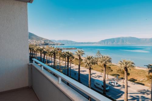 a balcony with a view of the beach and palm trees at DUKA Hotel in Vlorë