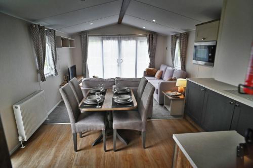 een eetkamer en een woonkamer met een tafel en stoelen bij Hobbit - Holiday Lodge in Longridge