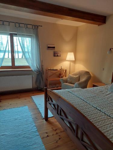1 dormitorio con 1 cama, 1 silla y 1 ventana en Gustiņi, en Baltezers