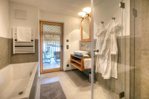 a bathroom with a shower and a tub and a sink at designchalets auf 685 in Reit im Winkl