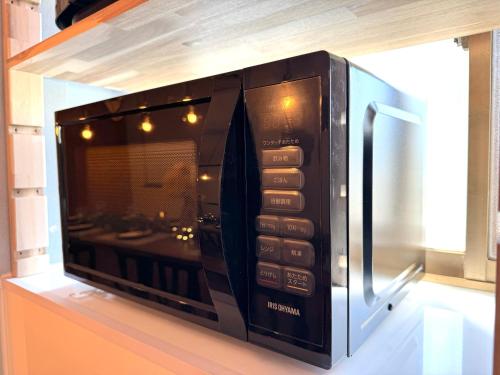 a microwave oven sitting on top of a shelf at 【海水浴場まで3分！】リノベーションされた古民家を貸切！ANGO KUJUKURI3 in Kujukuri