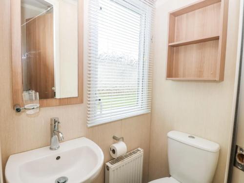 une salle de bain avec un lavabo et des toilettes et une fenêtre dans l'établissement Dog Friendly 3 Bedroom Static Caravan In Fritton, à Belton