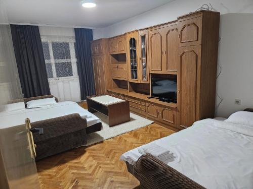 a bedroom with two beds and a cabinet with a tv at Apartman NINA in Kuršumlija