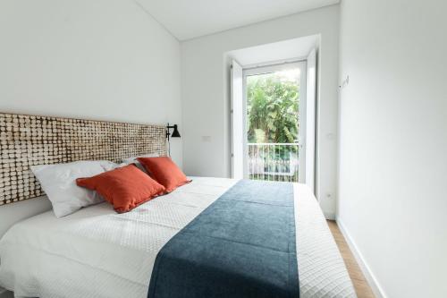 a white bedroom with a large bed with orange pillows at Brum Design Apartments I in Ponta Delgada