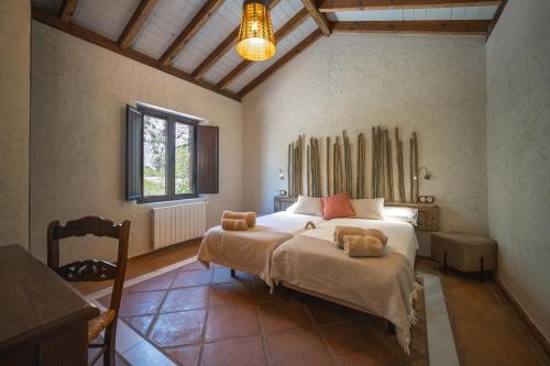 a bedroom with a bed with two stuffed animals on it at Eco Hotel Cueva del Gato in Benaoján