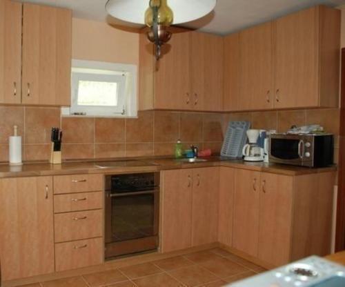 a small kitchen with wooden cabinets and a microwave at Ruhig gelegenes Ferienhaus für erholsamen Urlaub auf dem Land inmitten der Thermenregion Sloweniens in Mala Nedelja