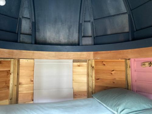 a bed in a room with wooden walls at Moon Pod in Westfield