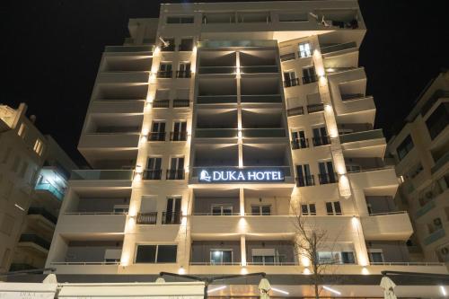 a white building with a blue hotel sign on it at DUKA Hotel in Vlorë