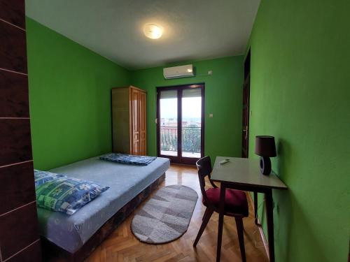 a bedroom with green walls and a bed and a desk at PEKOVIĆ in Bar