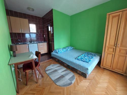 a green room with a bed and a table and a desk at PEKOVIĆ in Bar