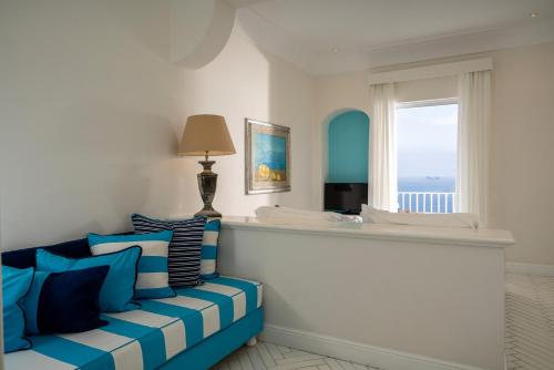 a living room with a blue couch and a window at Tramonto d'Oro in Praiano
