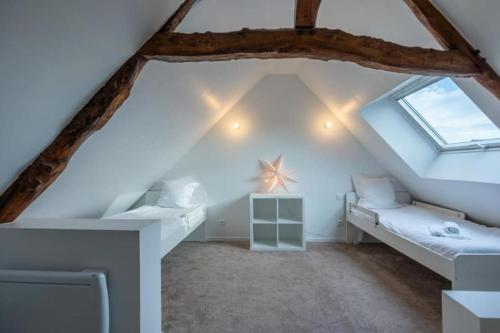 Cette chambre mansardée comprend un lit et une fenêtre. dans l'établissement Maison de famille au coeur d’Asnelles plage à 500m, à Asnelles