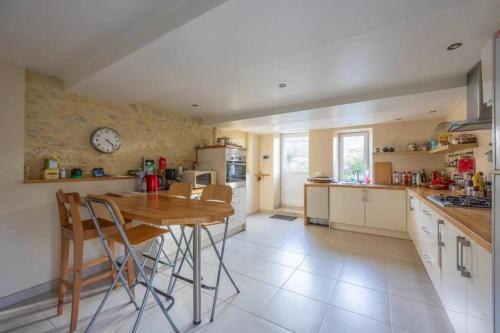 une cuisine avec une table et une horloge au mur dans l'établissement Maison de famille au coeur d’Asnelles plage à 500m, à Asnelles
