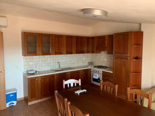 uma cozinha com armários de madeira e uma mesa com cadeiras em Casa Vacanze Muzzicato em Partinico