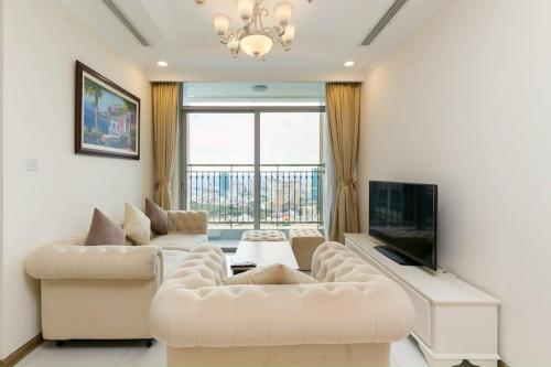 - un salon avec deux canapés blancs et une télévision dans l'établissement Vinhomes Apartment, à Hô-Chi-Minh-Ville