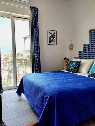 a bedroom with a blue bed and a large window at Sosò Art b&b in Positano