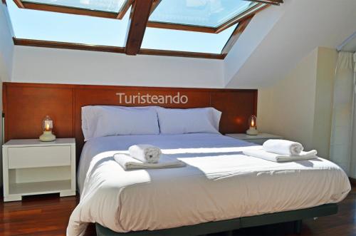 a bedroom with a bed with towels on it at Dúplex El Mochuelo: vistas al casco histórico, mucha luz y plaza de aparcamiento in San Vicente de la Barquera