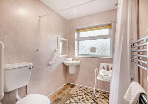 a bathroom with a toilet and a sink and a window at Sunbeam in Snettisham