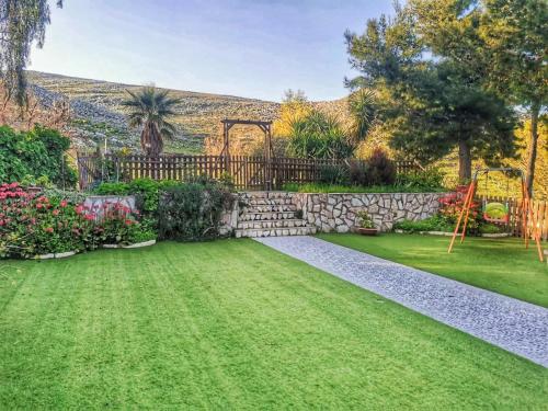 um jardim com uma parede de pedra e um parque infantil em Appartamento•Palermo em Torretta