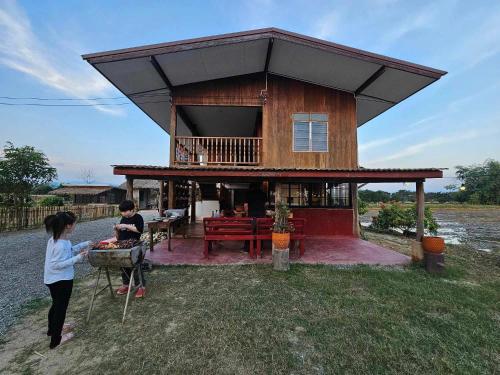 two people standing in front of a house at Ha Me Garden ฮามีการ์เด้น โฮมสเตย์ฝาง in Fang