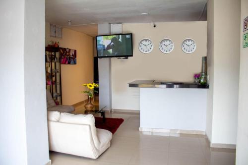 a living room with a couch and a tv on the wall at RUTA DEL MAR INN HOTEL in Santa Marta