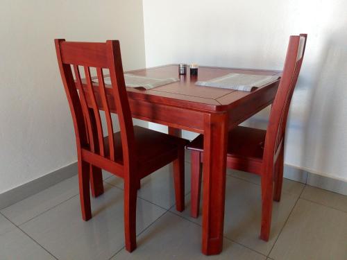 een houten tafel met twee stoelen en een tafel met papier erop bij Kulu Lodge Apartments in Lusaka