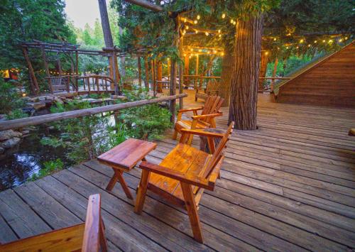 a wooden deck with chairs and tables and a tree at Arrowhead Pine Rose Cabins in Twin Peaks